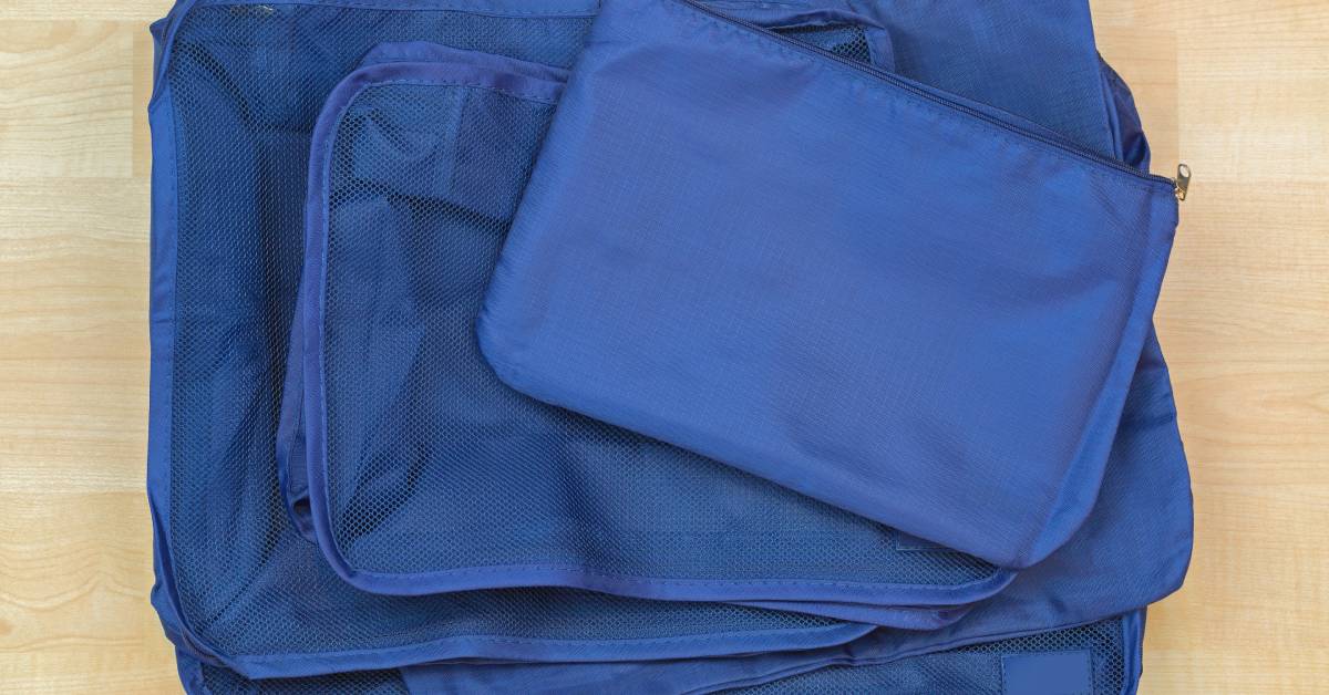 A stack of royal blue packing cubes. The cubes are in a variety of sizes and have mesh panels on the front.