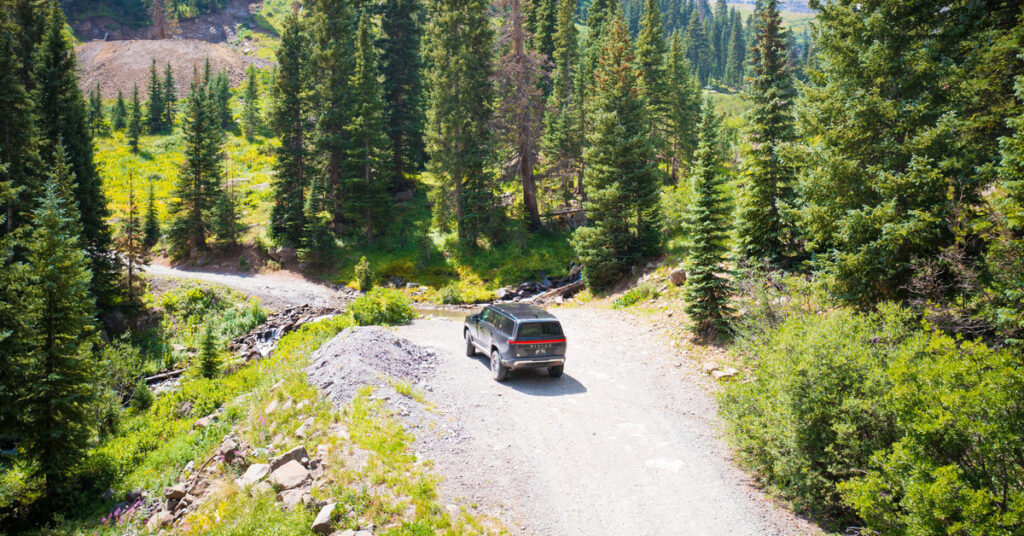 An off-roading vehicle parked on a well-cleared path surrounded by tall evergreens in Ouray, Colorado.